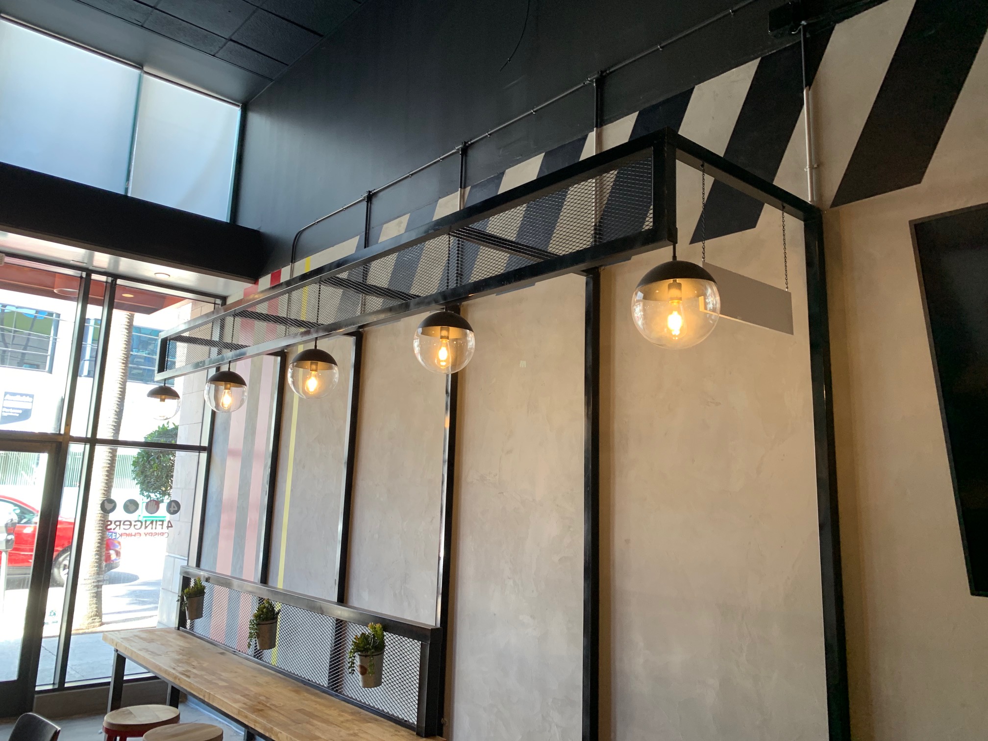 Bar counter detail with red stools and mesh railing planters