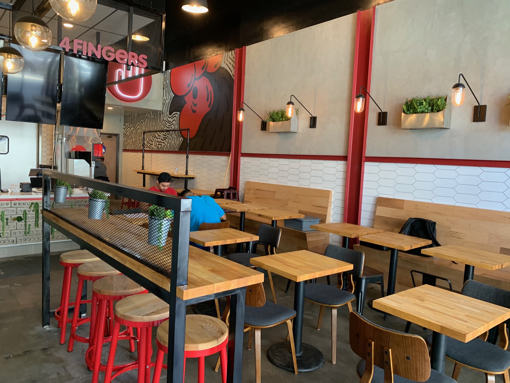 Dining area with branded mural wall, red columns, and wood bench seating